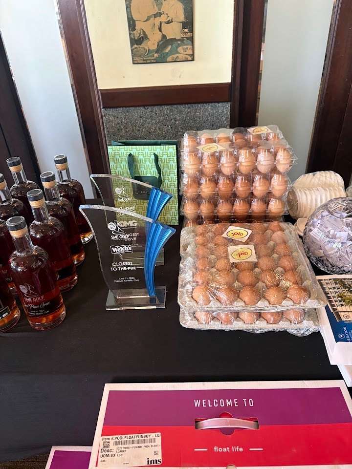 Mesa de premios de un torneo de golf con bandejas de huevos de punto.pio junto a un trofeo del torneo